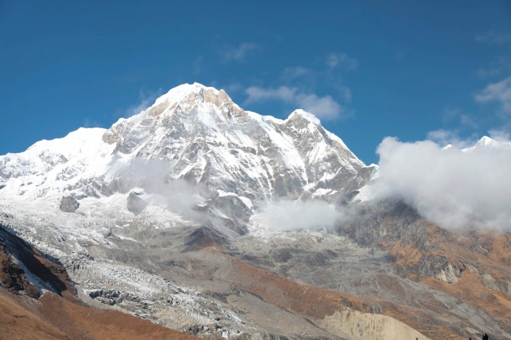Panoramic view of the Annapurna mountain range from the base camp at sunrise, with golden light on the snowy summits.
