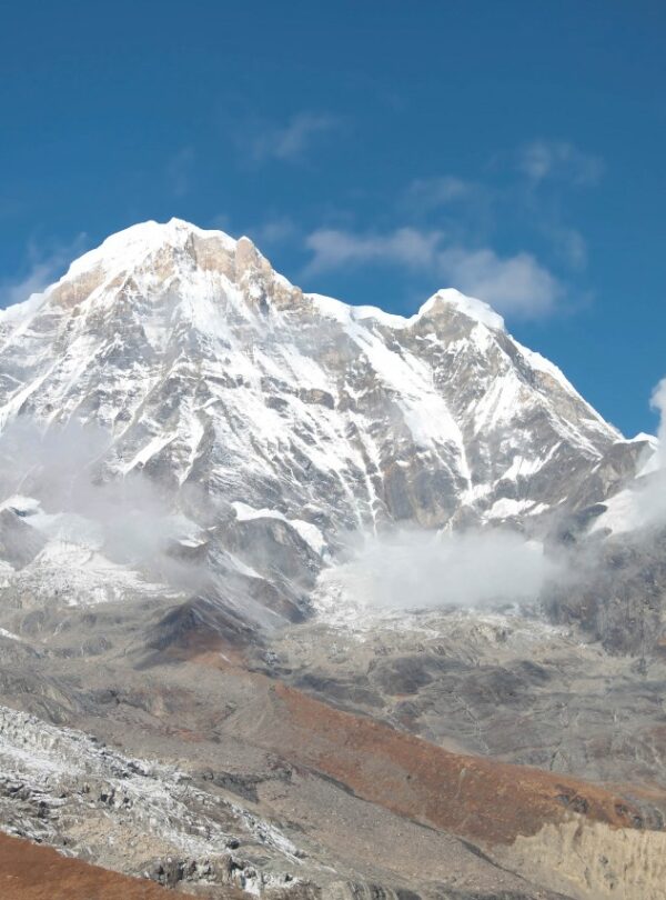 Panoramic view of the Annapurna mountain range from the base camp at sunrise, with golden light on the snowy summits.