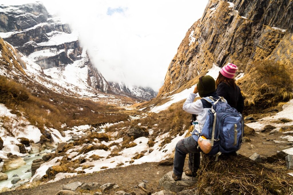 Trekkers walking through lush green trails on the way to Annapurna Base Camp with snow-capped peaks in the background.
