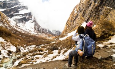 Trekkers walking through lush green trails on the way to Annapurna Base Camp with snow-capped peaks in the background.