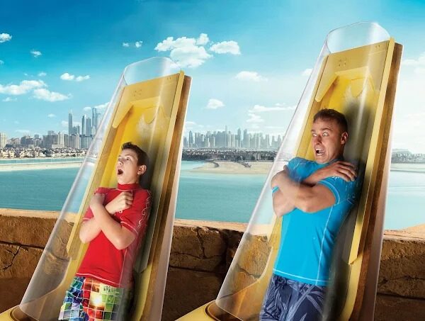 Adventurers sliding through a winding water tube at Atlantis Dubai