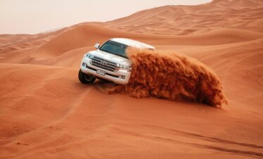 Luxury 4x4 driving over golden sand dunes during Dubai evening desert safari