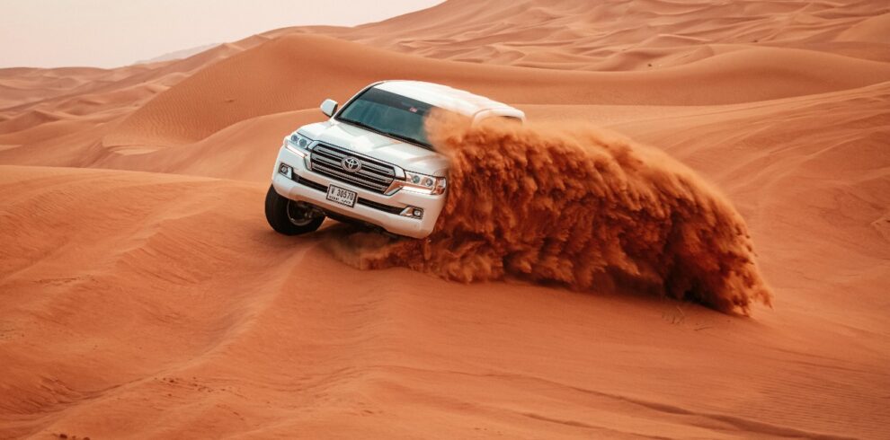 Luxury 4x4 driving over golden sand dunes during Dubai evening desert safari