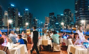 Tourists enjoying buffet dinner on a Dubai Creek dhow cruise at night