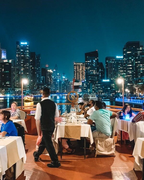 Tourists enjoying buffet dinner on a Dubai Creek dhow cruise at night