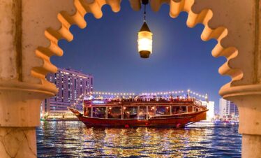 Traditional wooden dhow boat sailing on Dubai Creek during evening cruise