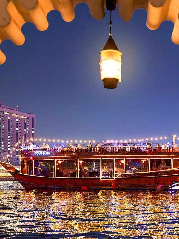 Traditional wooden dhow boat sailing on Dubai Creek during evening cruise